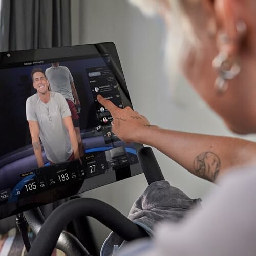 Person using an interactive fitness bike screen with virtual trainer.