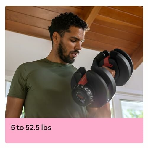 Man lifting adjustable dumbbell indoors.